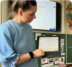 Foto einer Lehrerin mit blauem Pullover, die ein Tablet in der Hand hält, auf dem man sofatutor Inhalte sehen kann